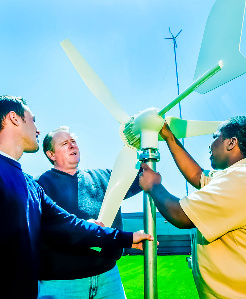two students and an instructor holding a wind propeller