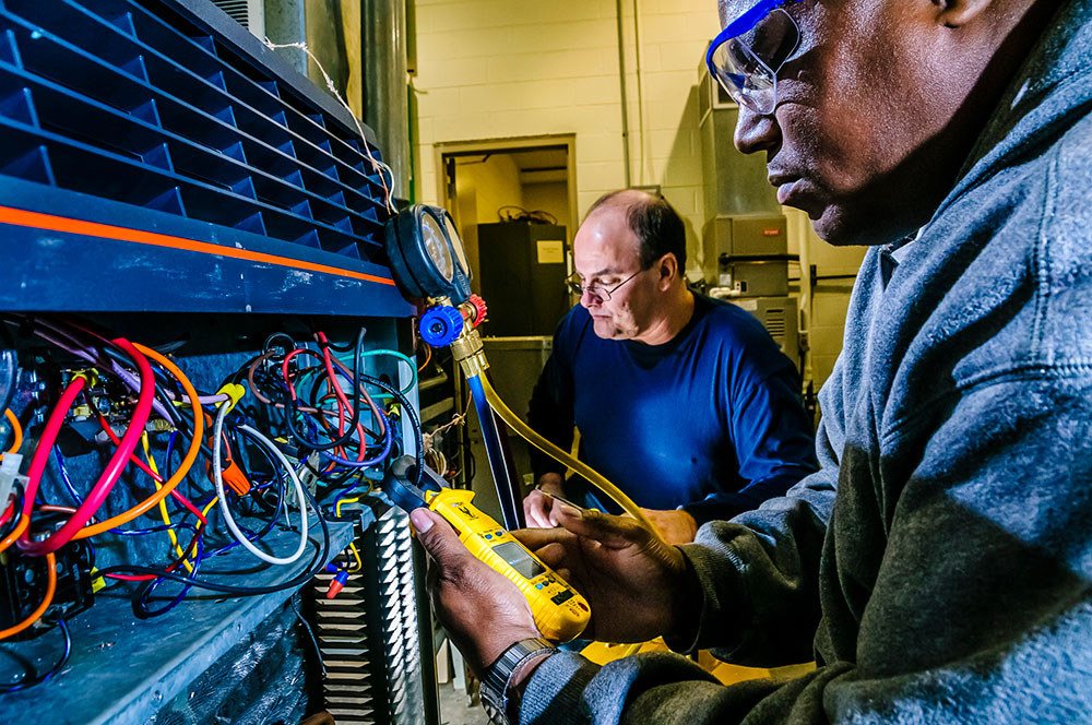 two men looking at HVAC control panel and wiring system
