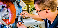 A student concentrates closely as he performs aviation maintenance
