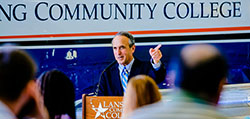 President Dr. Brent Knight stands at a podium in front of an LCC airplane, announcing the Partnership with Delta Air Lines