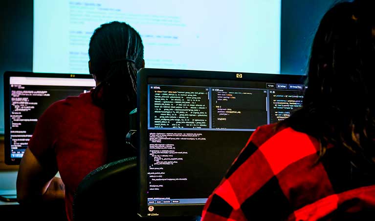 students looking at code on computers in a classroom computer lab