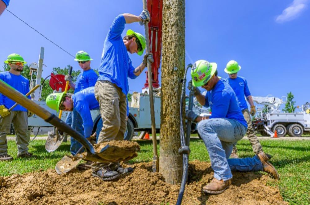 students attaching wire at the base of a pole
