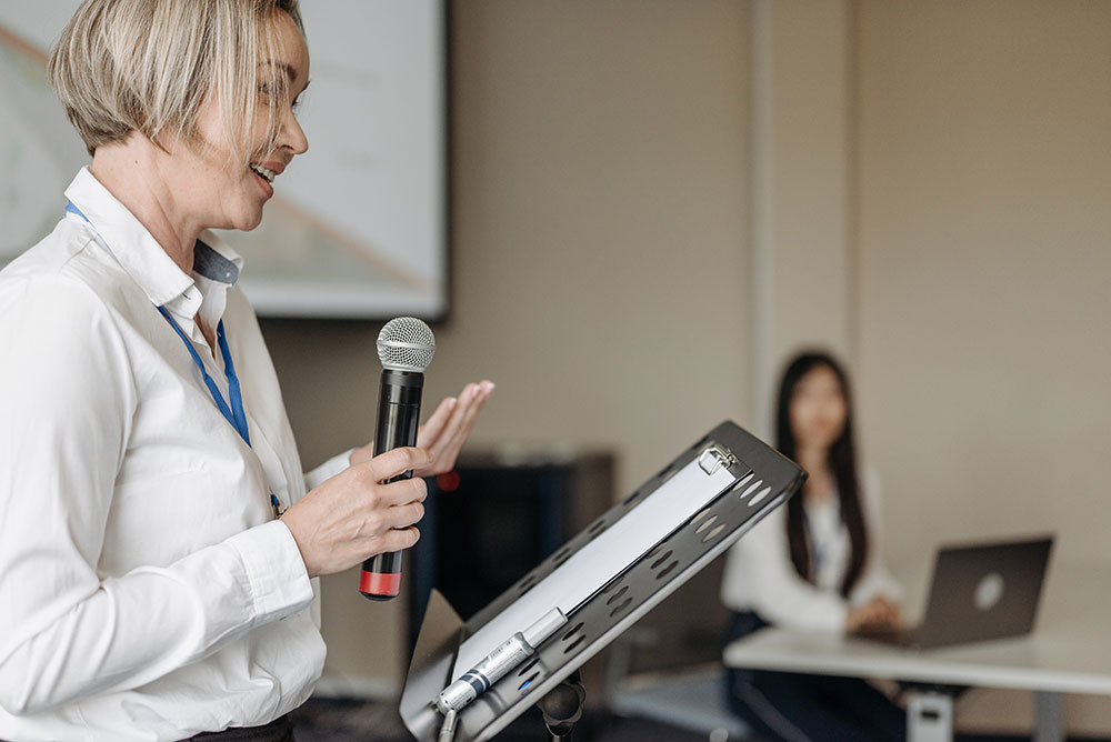 woman speaking at a podium in a classroom