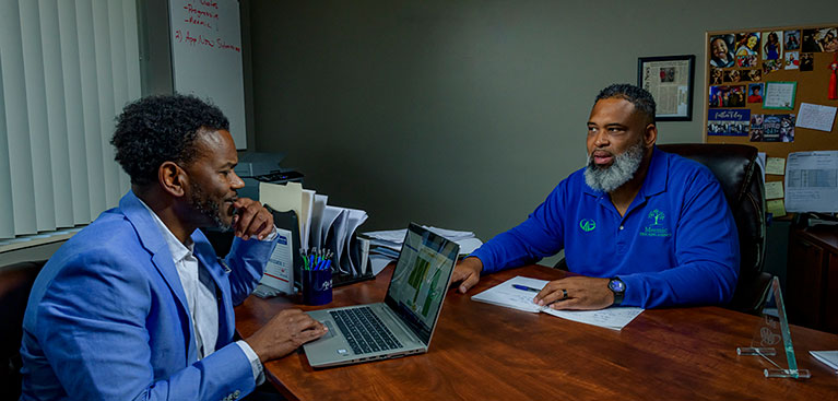 two men sitting at a desk doing business