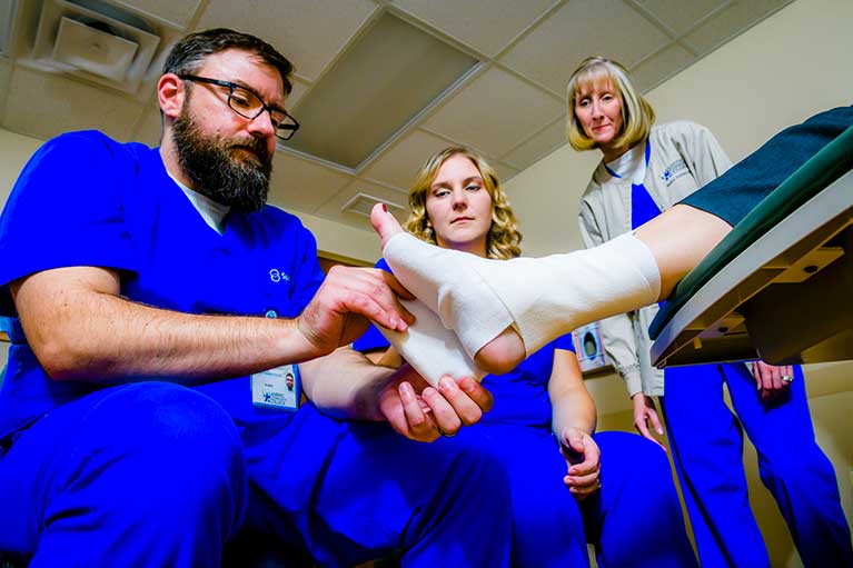 Man tapes a person's foot with medical tape