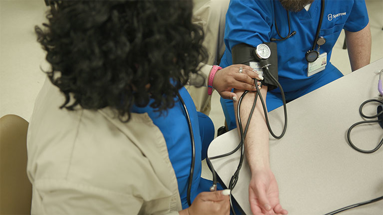 Nurse checking another nurses blood pressure