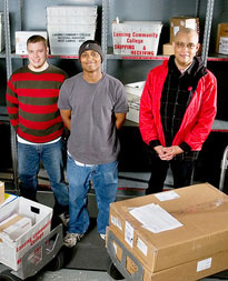 Three mail services staff standing together with boxes