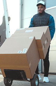 Man pushing cart with three boxes of deliveries