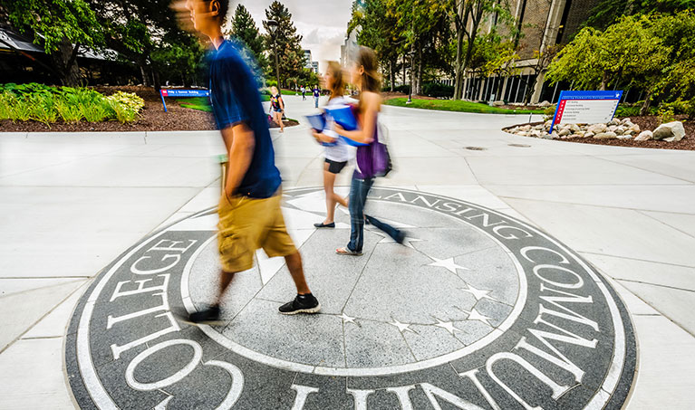 students walking across the College Seal on campus