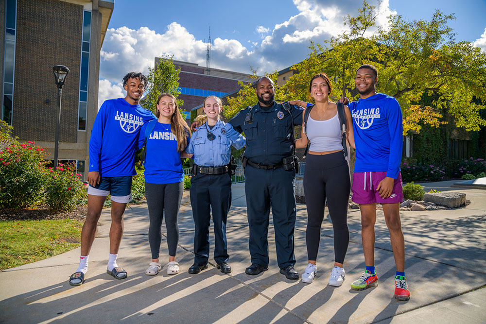 Police officer, a police cadet and four students posing in a row for a photo