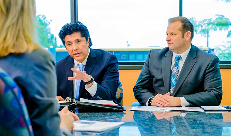 people in suits in a meeting sitting at a table talking