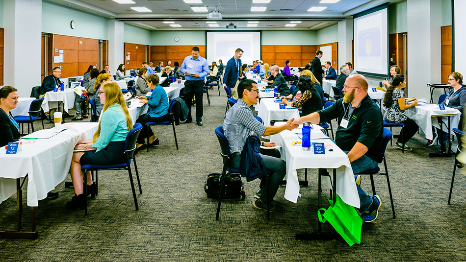 People sit together at tables and discuss in the West Campus Conference Room