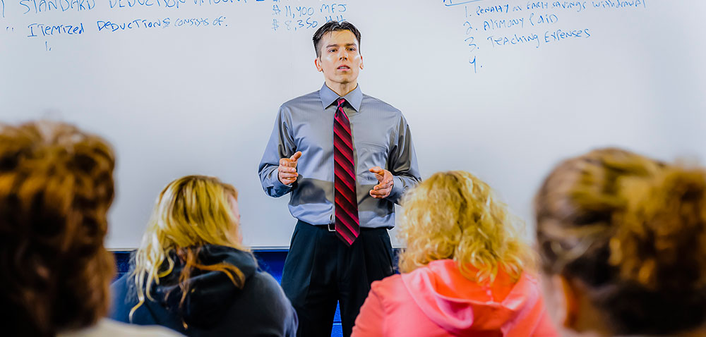 a young man explaining career advancement tips on a whiteboard while his audience listens intently