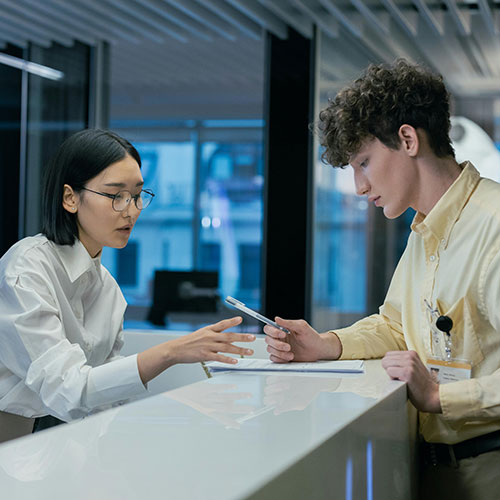 Person helping two others at a front desk