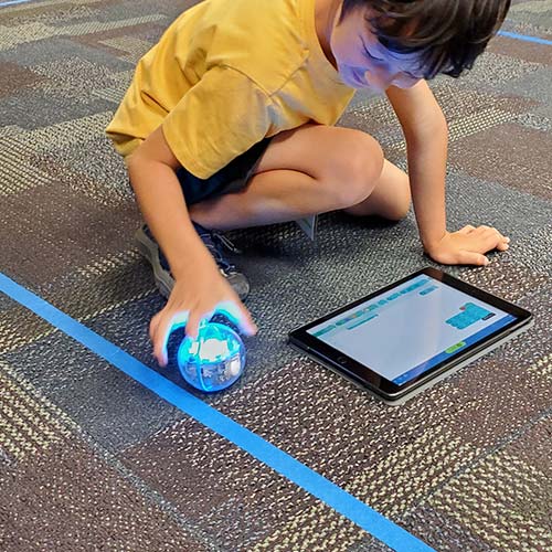 Student playing with a coded robot