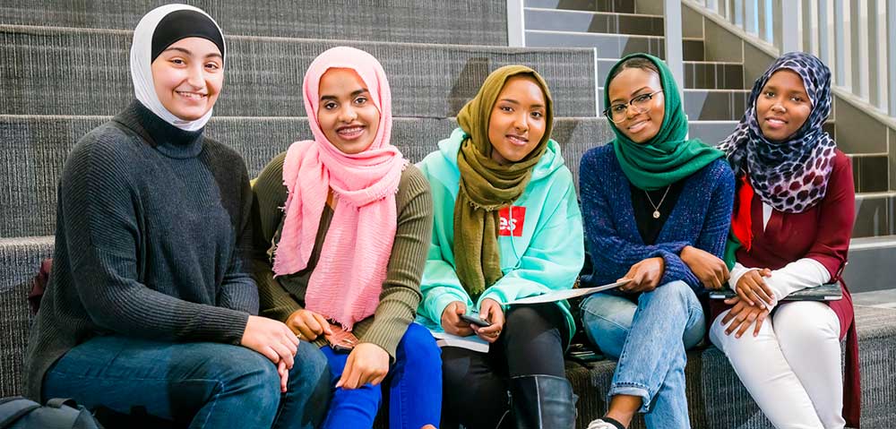 group of muslim students sitting in a row at gannon commons
