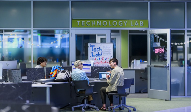 a student with a library instructor at a computer in the technology lab