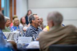 Group of people listening to the presenter while seated at tables