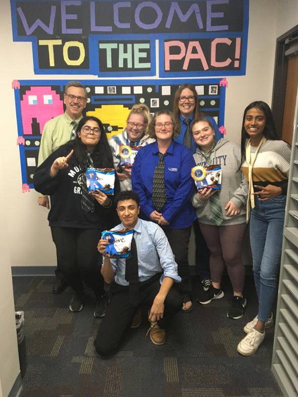 Mark Khol with several employees at LCC East showing off their sticky note project