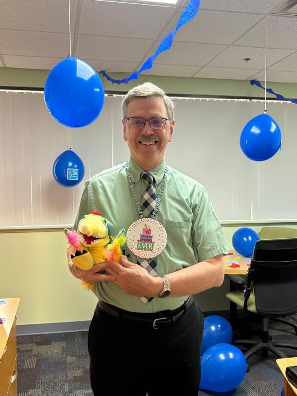 Mark Khol holding his bday present and wearing a bday necklace