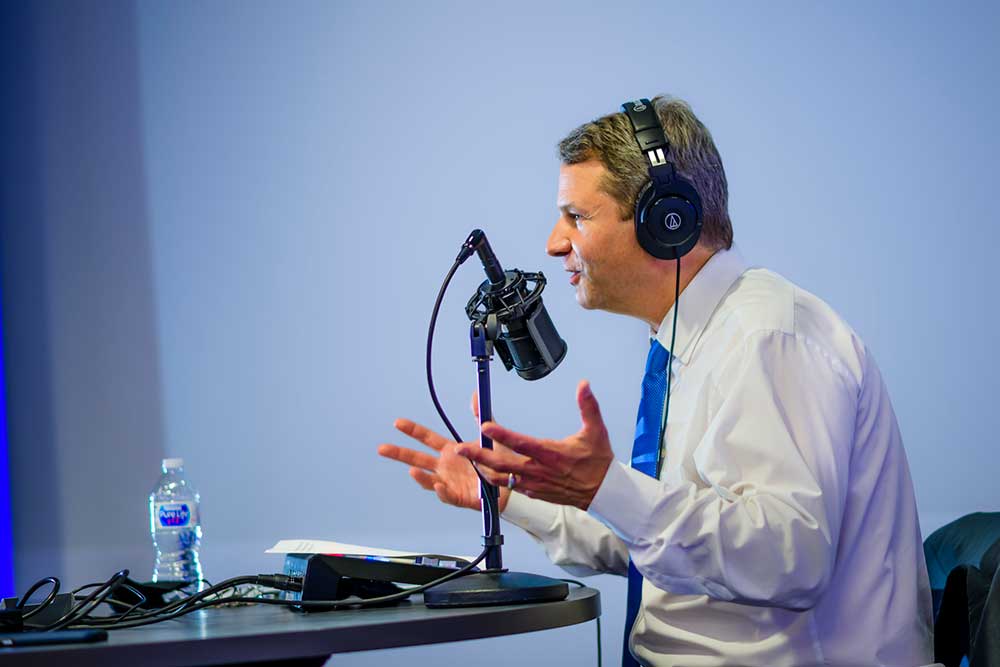 dr. robinson speaking into a microphone while recording his podcast