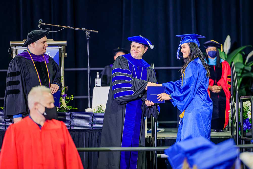 dr. robinson shaking a students hand at graduation