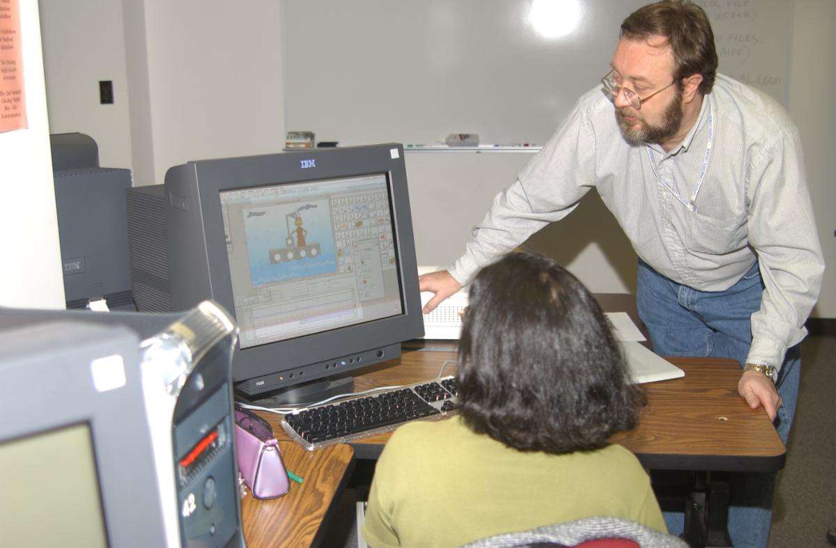 Two people looking at a computer with an animation program on the screen.