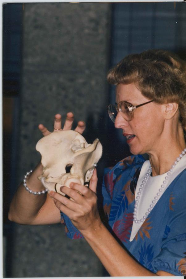 A woman holds up a bone.