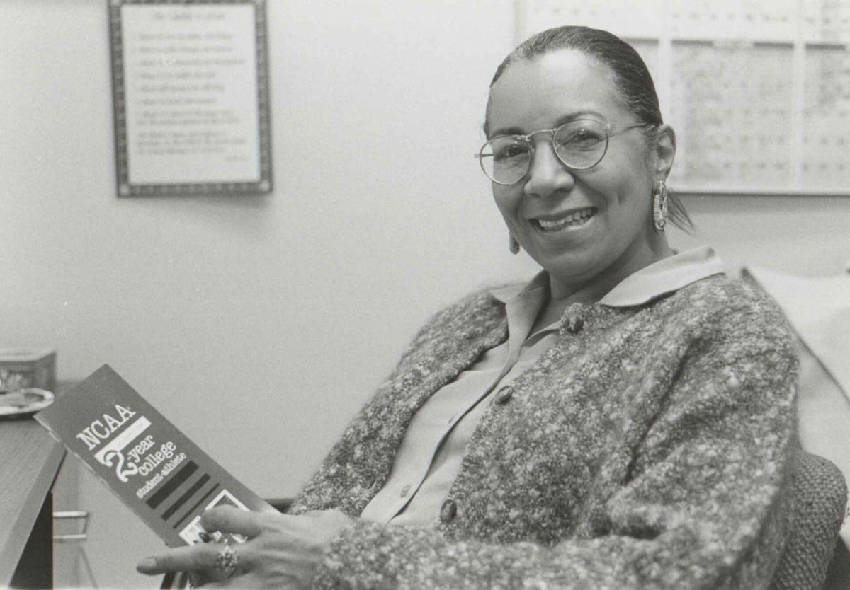 A woman sits at a desk holding an NCAA pamphlet.
