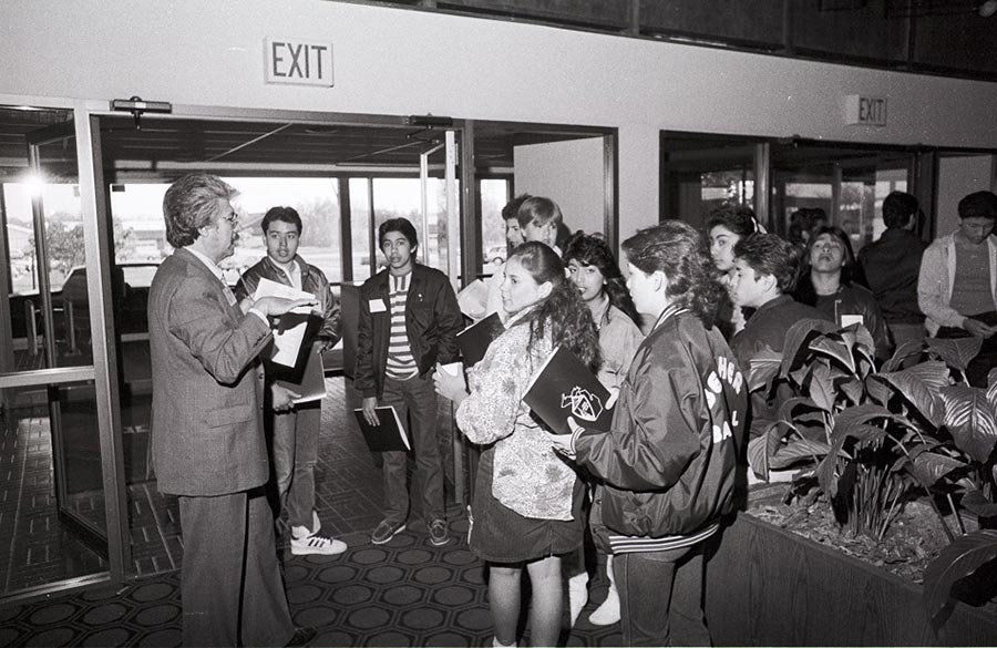 Rogelio “Rollie” Alfaro, a bi-lingual Counselor at LCC, talks with a group of LCC students attending the Michigan Hispanic Education Conference - ca. 1980s