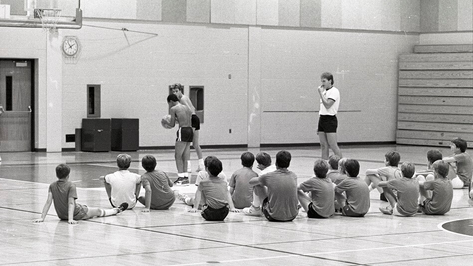 Young students watch another student at the free-throw line at a baskeball camp held in the Gannon Gymnasium - ca. 1980s