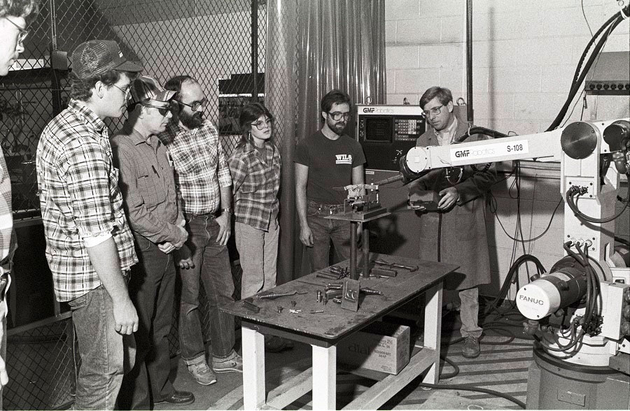 Welding instructor Bill Eggleston (right) demonstrates a welding robot in the welding lab located in the Gannon Vocational-Technical Building which was the south end of the current Gannon Building - ca. 1980s