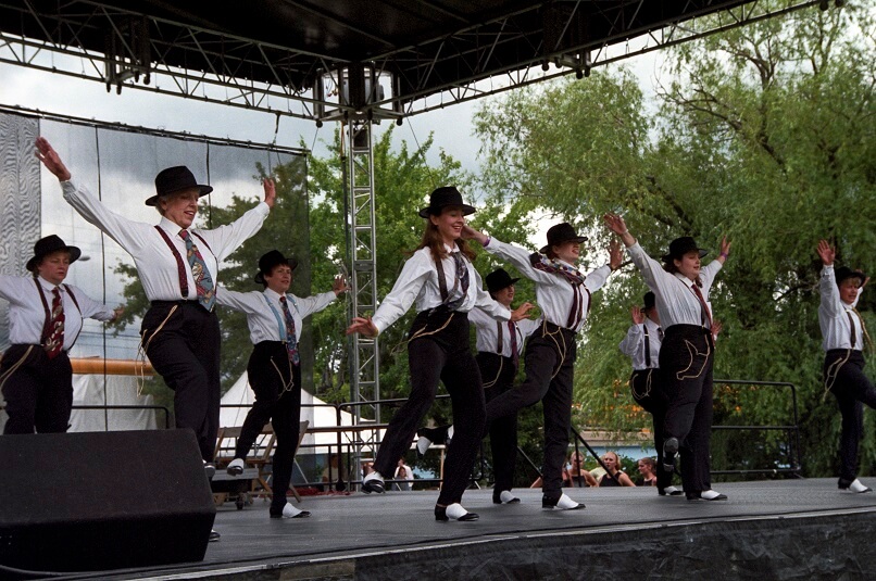 Women in costume perform a tap-dance routine on stage at Adado Riverfront Park - ca. 2000s