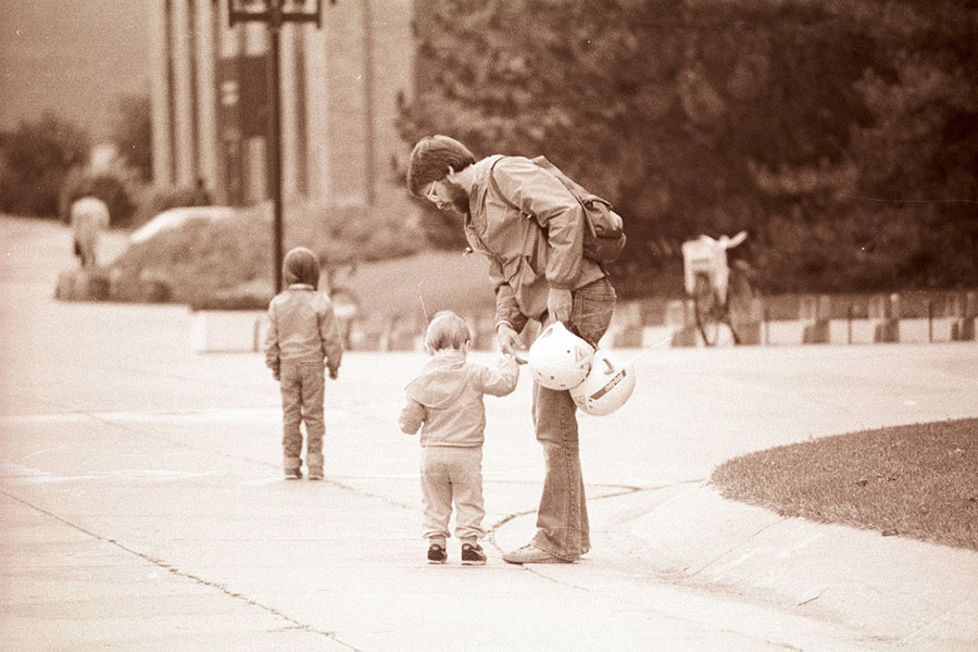 A man walks through the downtown campus with his kids - ca. 1980s