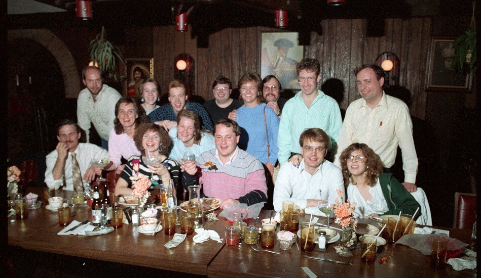 Media Services Department staff members pose for a group photograph during a celebration dinner for Judith Keely held at Ramon's South on Washington Avenue in Lansing. Standing top row (from left): Paul Price (FT Staff - Video Production), Bonnie (Weathers) McGraw (PT Staff - Audio Production), Rob Edwards (PT Staff - Video Production), Roy Harter (PT Staff - Video Engineering), Stephanie Schafer (Student Employee - Video Production), Rob VanOeveren (FT Staff - Video Engineering), Marc Smyth (FT Staff - Video Distribution), Fred Stephens (FT Staff - Video Production). Standing middle row (from left): Jean Hall (PT Staff - Video Production), Kate Merrill (PT Staff - Audio Production). Seated (from left): Bob Baxter (PT Staff - Video Production), Judith Keely (PT Faculty - Media Technology), Dennis Clark (FT Staff - Video Engineering), Steve Conn (Student Employee - Video Production), Peg Howland (PT Staff - Video Engineering). - ca. 1988.