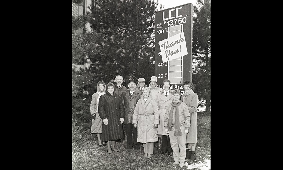 A group stands next to LCC's Capital Area United Way progress tracking sign outside of the Arts & Sciences building - ca. 1980s-1990s