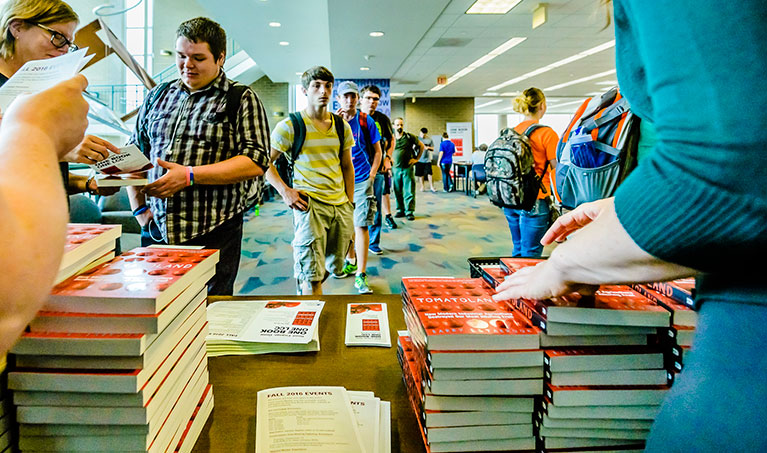 students at the L C C library form a line behind a table giving out free books and pamphlets