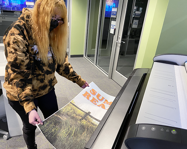 student taking their poster out of the large format printer