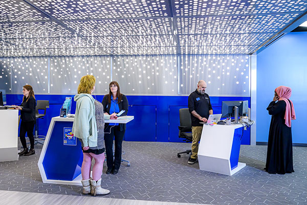 students speaking with employees in the library help zone