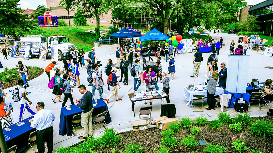 Outdoor event with many students interacting and vistion tables